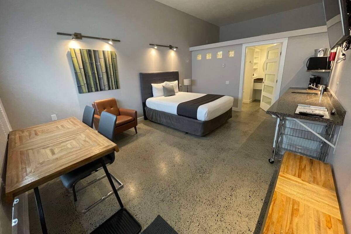 Une chambre d’hôtel de taille réduite, comprenant un lit, un bureau, une chaise et une kitchenette.