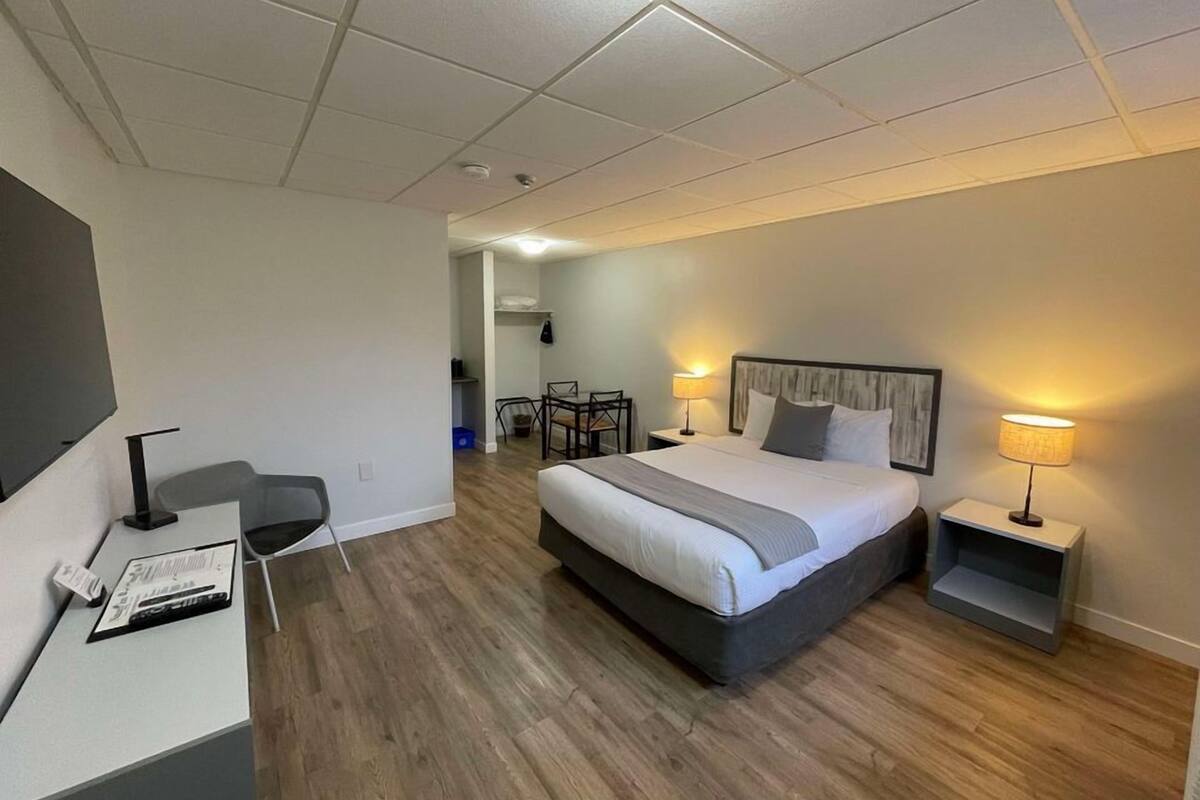 Une chambre d’hôtel moderne, dotée d’un grand lit, de tables de chevet avec des lampes, d’un bureau avec une chaise et d’un téléviseur.