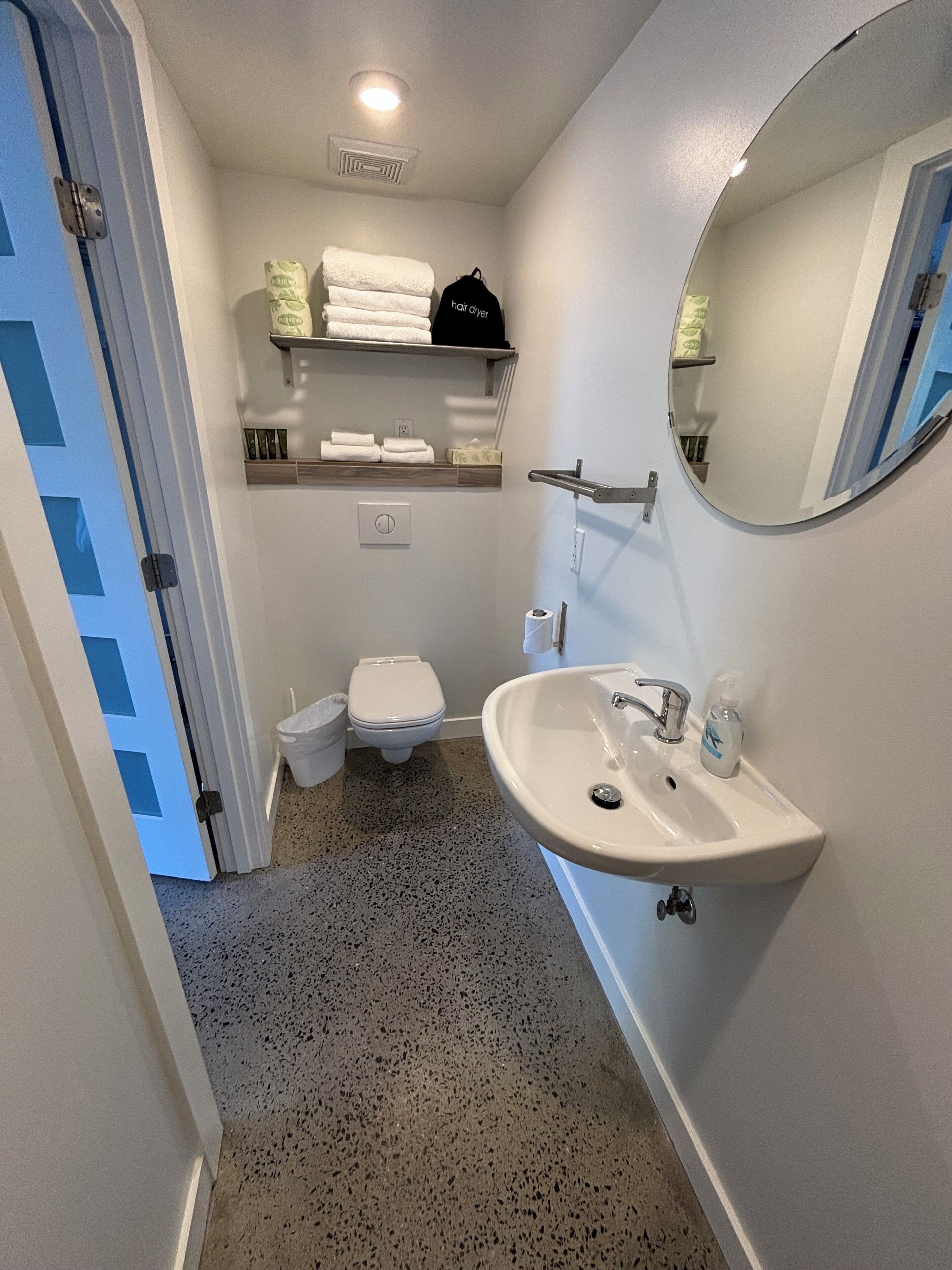 A bathroom with a white sink, a toilet, a mirror, and a towel rack.
