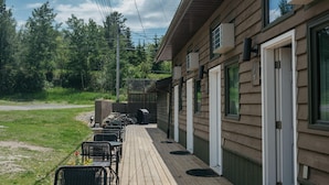 Une terrasse en bois avec des sièges extérieurs et un bâtiment doté de nombreuses portes et fenêtres.