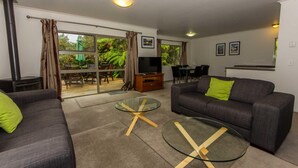A modern living room with a sofa, a glass coffee table, and a TV.