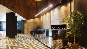A modern lobby with a herringbone floor pattern, a reception desk, and a large potted plant. - Russia Hotel Skopje (Skopje)