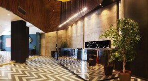Een moderne lobby met een visgraatvloer, een receptiebalie en een grote potplant.