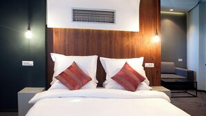 A hotel room with a bed, two bedside lamps, a chair, and a wall-mounted air vent. - Russia Hotel Skopje (Skopje)