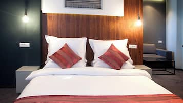 A hotel room with a bed, two bedside lamps, a chair, and a wall-mounted air vent.