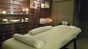A spa room with a massage table, towels, candles, and a mirror. - Russia Hotel Skopje (Skopje)