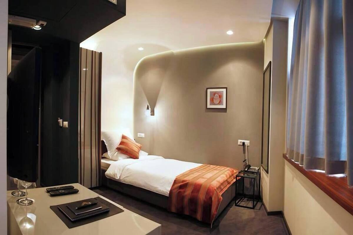 Une chambre d’hôtel avec un lit, une table de chevet, une lampe et un tableau au mur.