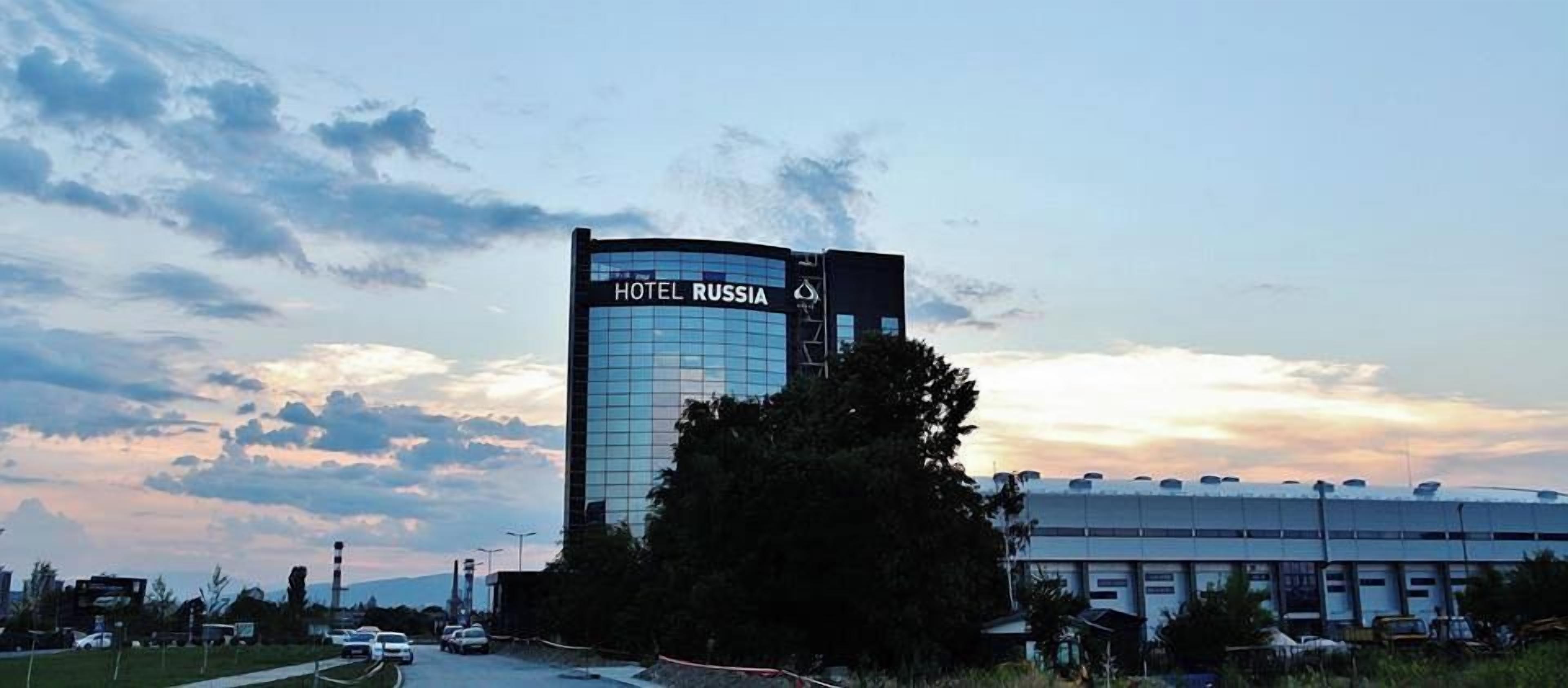 A modern hotel building with a glass facade and a sign reading 'HOTEL RUSSIA.'