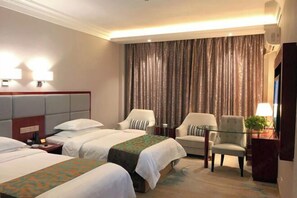 Habitació d'hotel amb dos llits, un sofà, una cadira, un televisor i una làmpada.