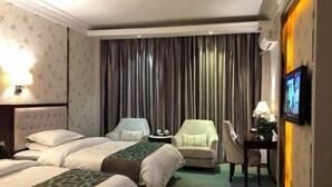 Habitación de hotel con dos camas, televisor, escritorio con lámpara y una silla.