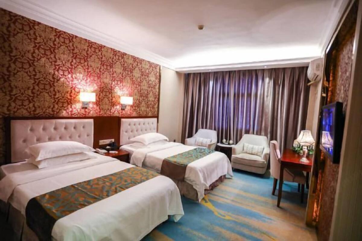 Une chambre d’hôtel avec deux lits, un canapé, une télévision et un bureau.