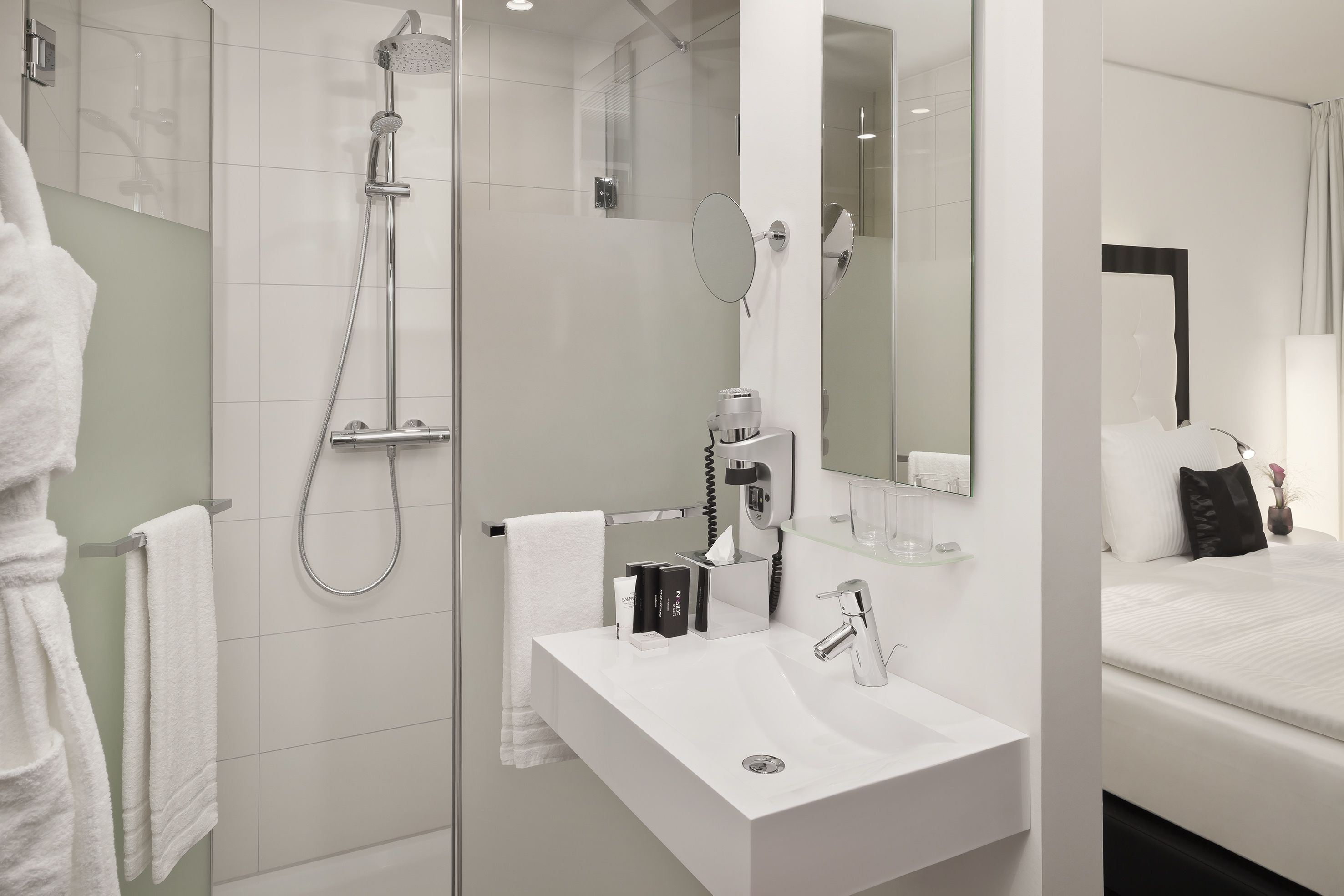 A modern bathroom with a shower, a sink, and a mirror.