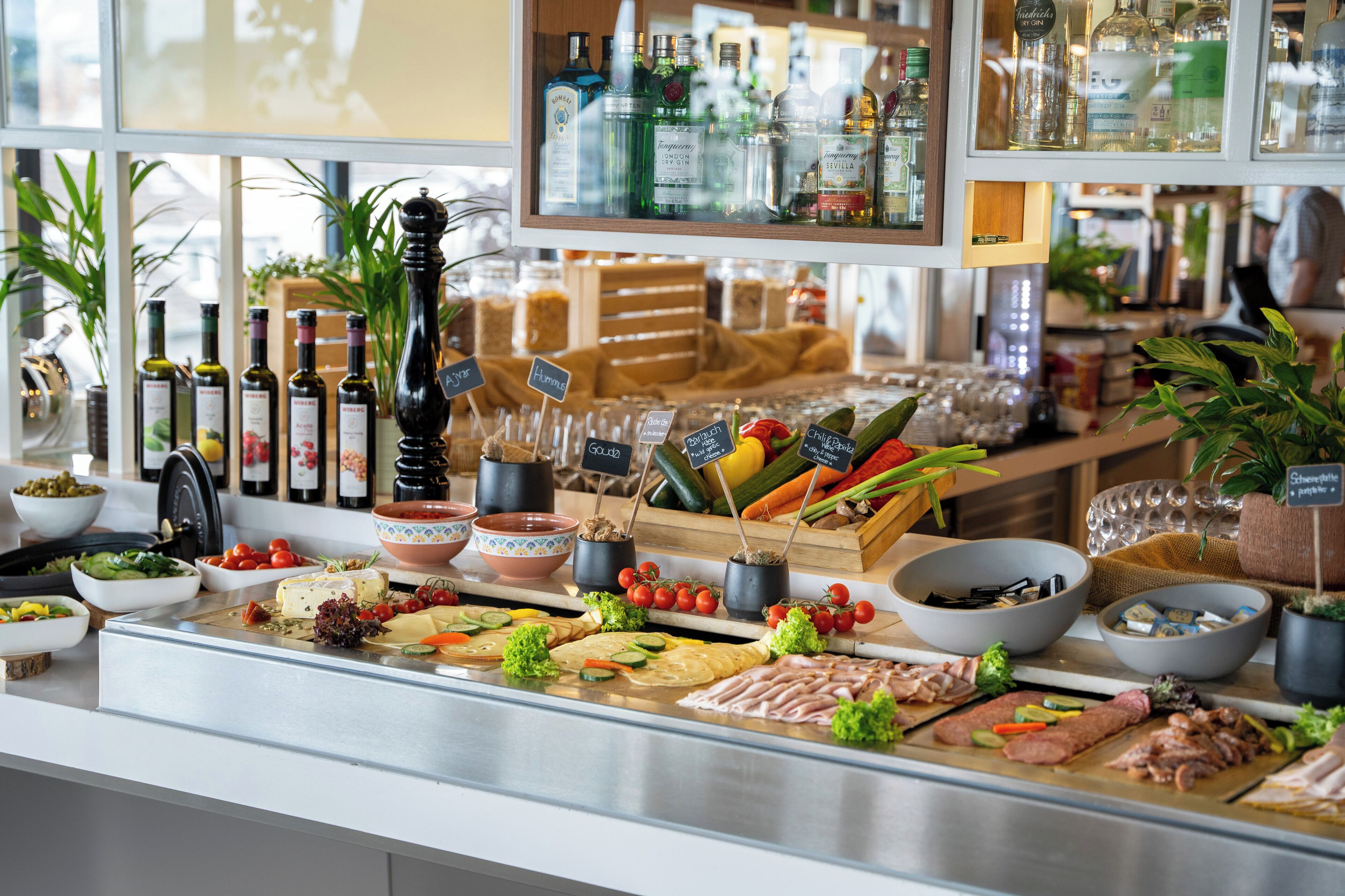 A deli counter with various meats, cheeses, and vegetables. There are also bottles of olive oil and other condiments.