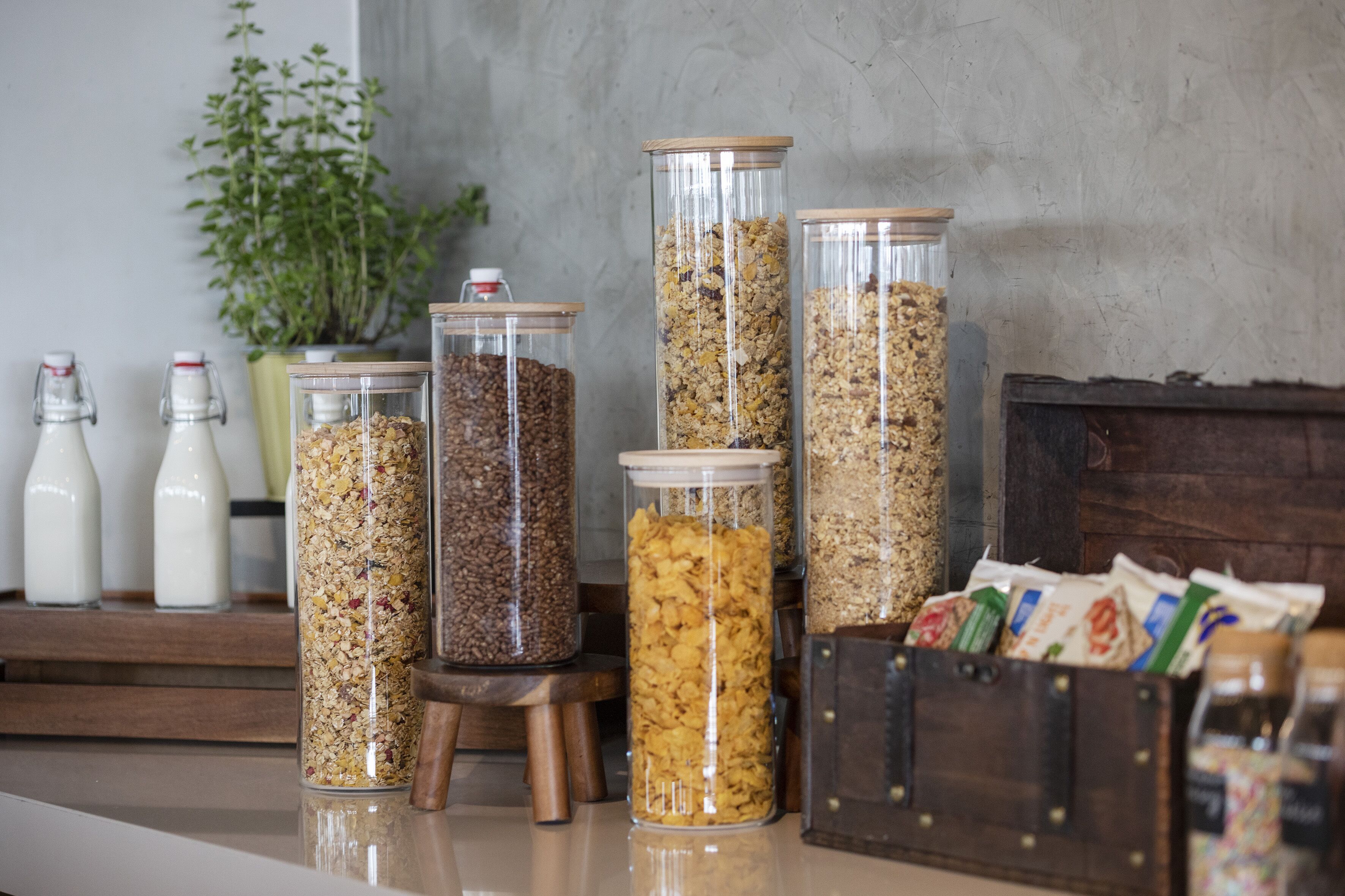 A kitchen counter with various food items, including jars of granola and a wooden box of snacks.