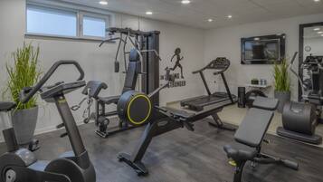 A gym with cardio machines, a bench, and a wall with motivational text.
