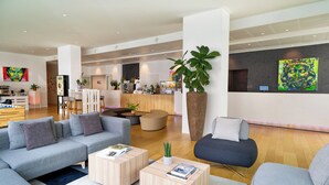 Un moderno vestíbulo de hotel con mostrador de recepción, zonas de estar y obras de arte en las paredes.