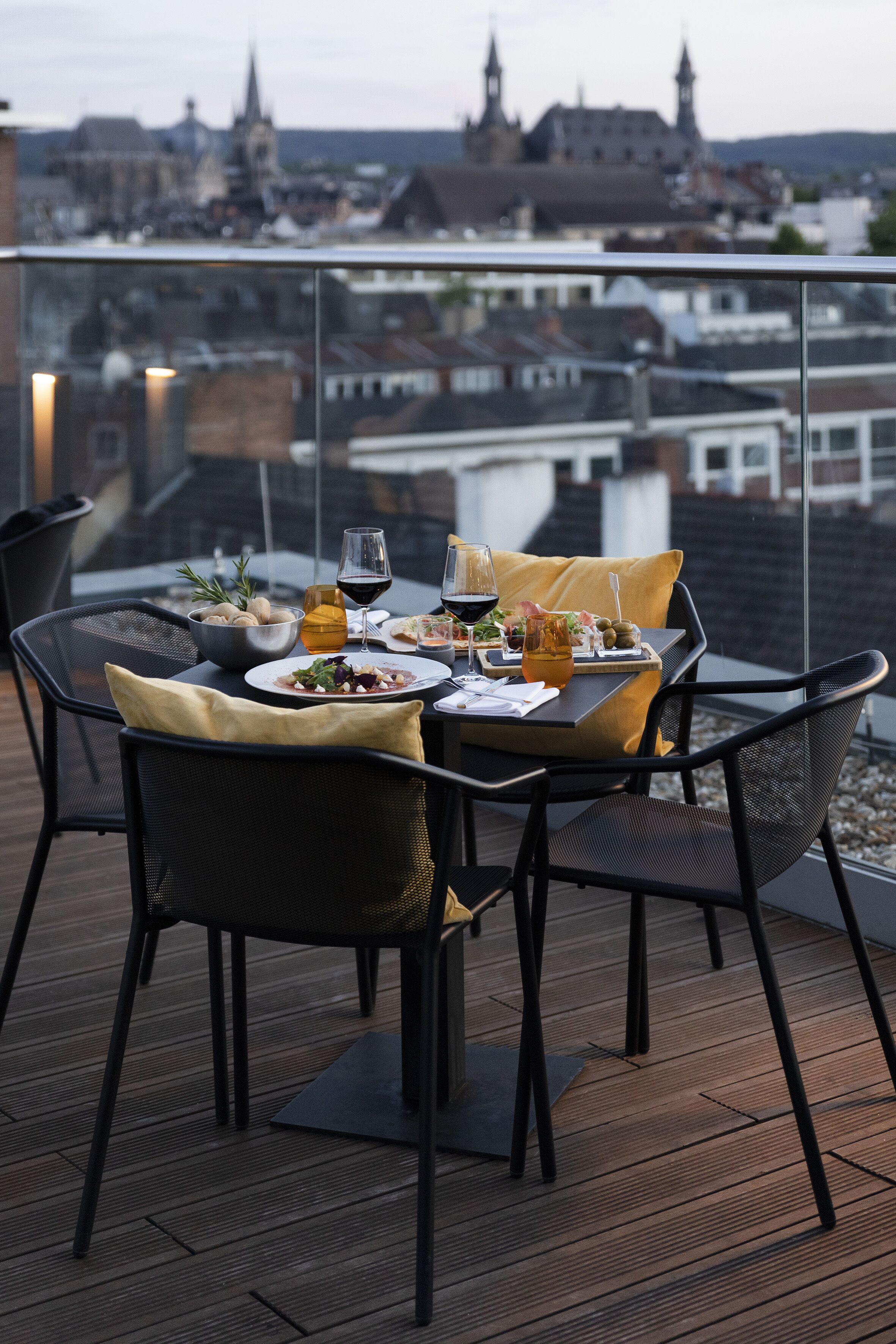 Ein Esstisch mit Stühlen auf einem Balkon mit Blick auf eine Stadtlandschaft.
