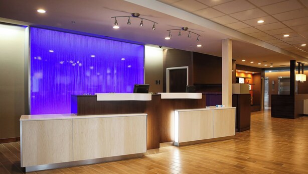 A reception area with a modern design, featuring a reception desk, a blue accent wall, and a wooden floor. - Fairfield Inn & Suites by Marriott Madison Verona (Verona)