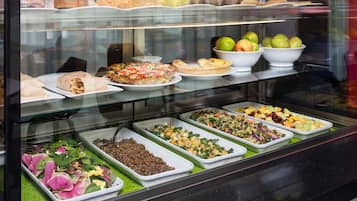 A buffet with various food options including salads, fruits, and pastries.