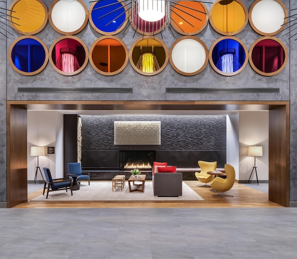 Un lobby moderno con chimenea, zona de estar y una pared de espejos circulares.