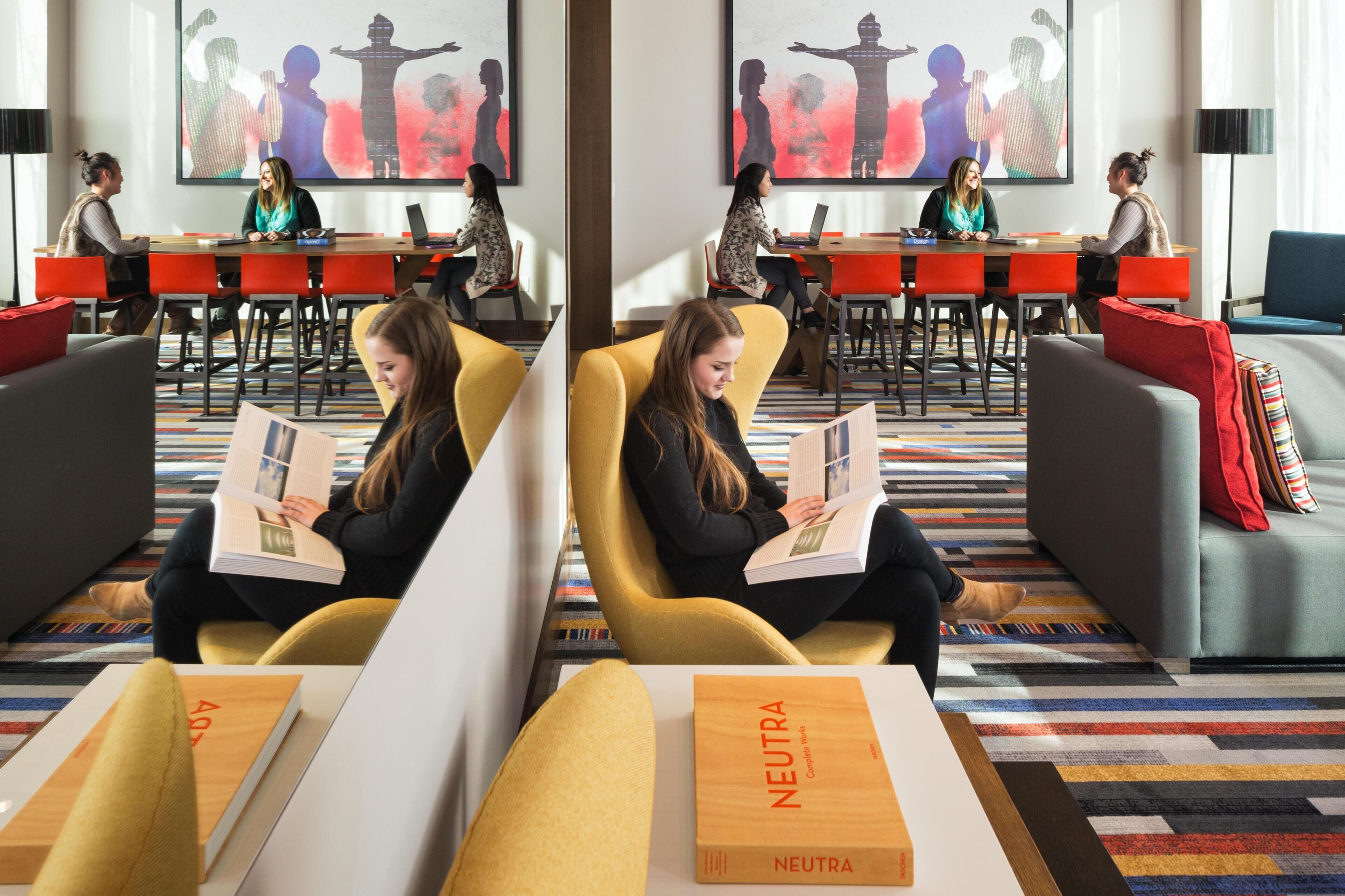 A modern lounge area with seating, tables, and artwork on the walls.