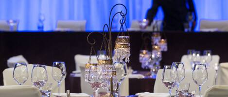 Una mesa dispuesta para un evento de cena formal, con cristalería de cristal y candelabros.
