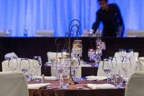A table set for a formal dining event with crystal glassware and candle holders.