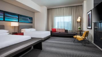 Habitación de hotel con dos camas, un sofá, una silla, un escritorio y un ventanal con cortinas.
