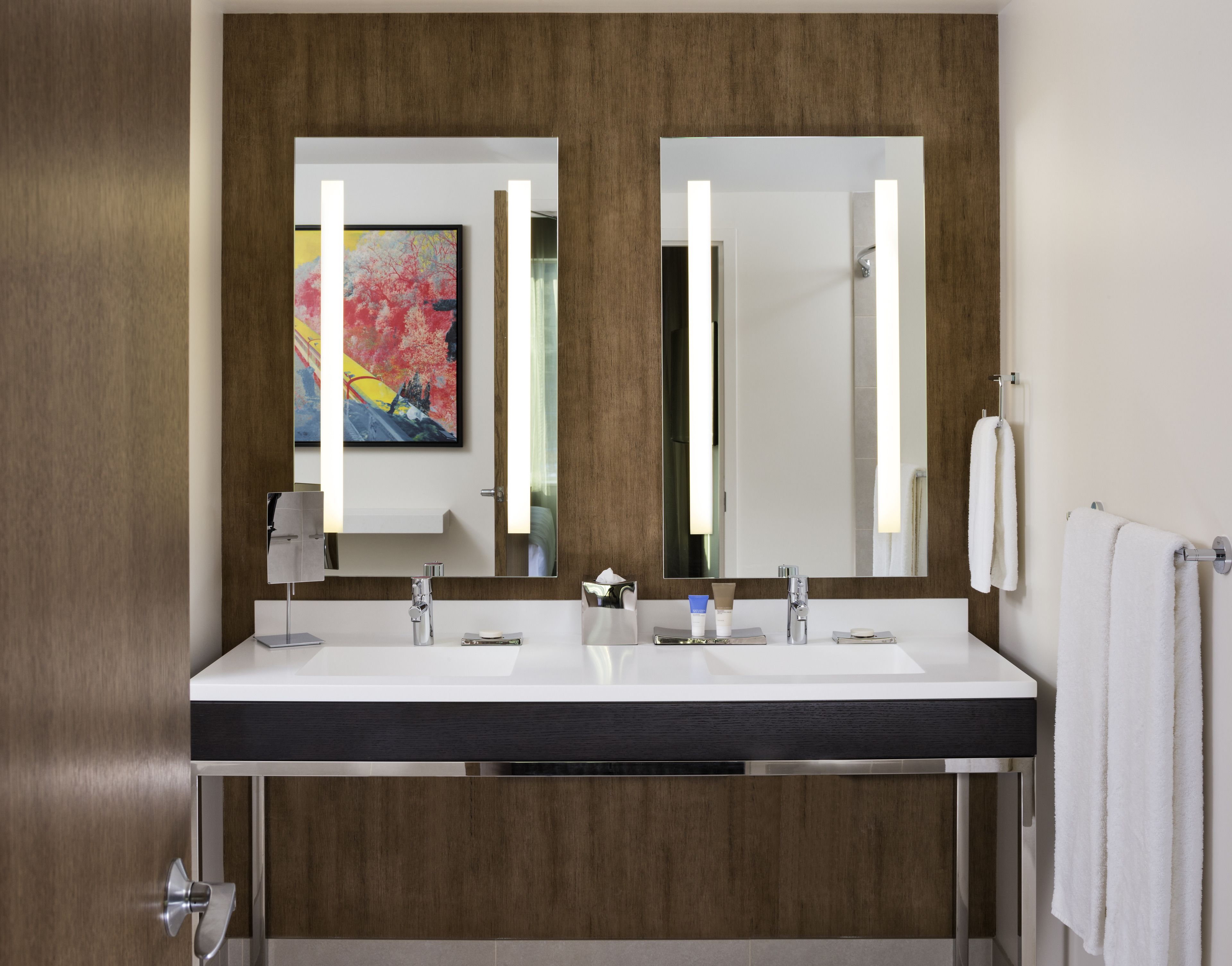 A modern bathroom with a double sink, a large mirror, and a wooden panel design.