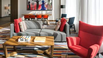 A modern living room with a sofa, a red armchair, a coffee table with books, and a colorful striped rug.