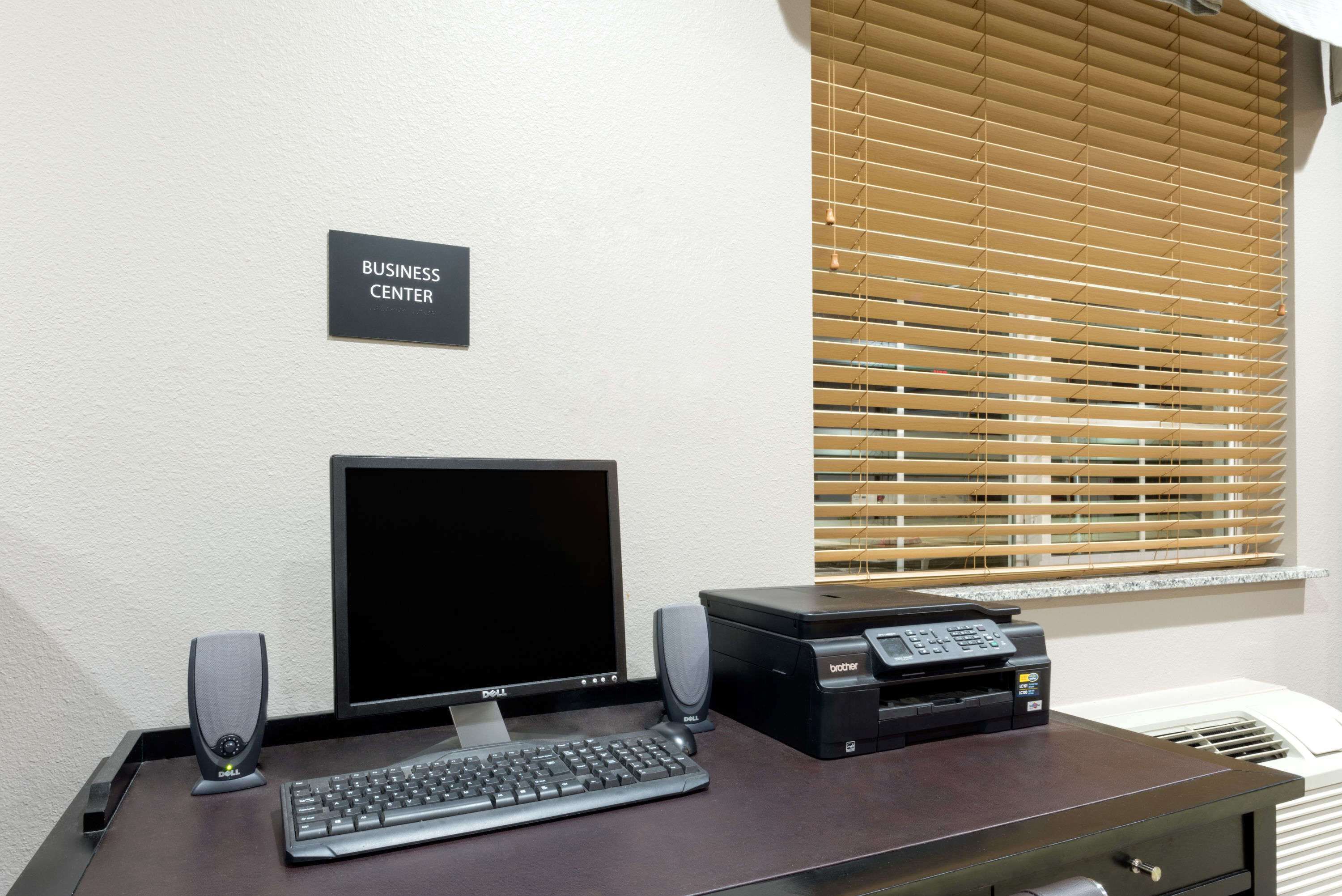 Escritorio de centro de negocios con computadora, teclado, bocinas e impresora.