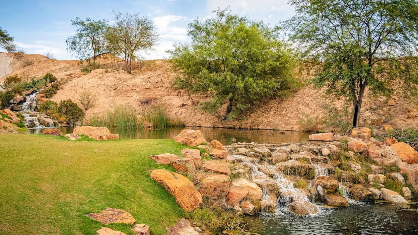 A natural landscape with a pond, rocks, and trees.