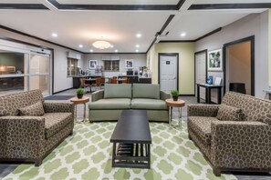 A modern hotel lobby with a sofa set, a coffee table, and a kitchen area in the background. - Super 8 by Wyndham Colorado City (Colorado City)