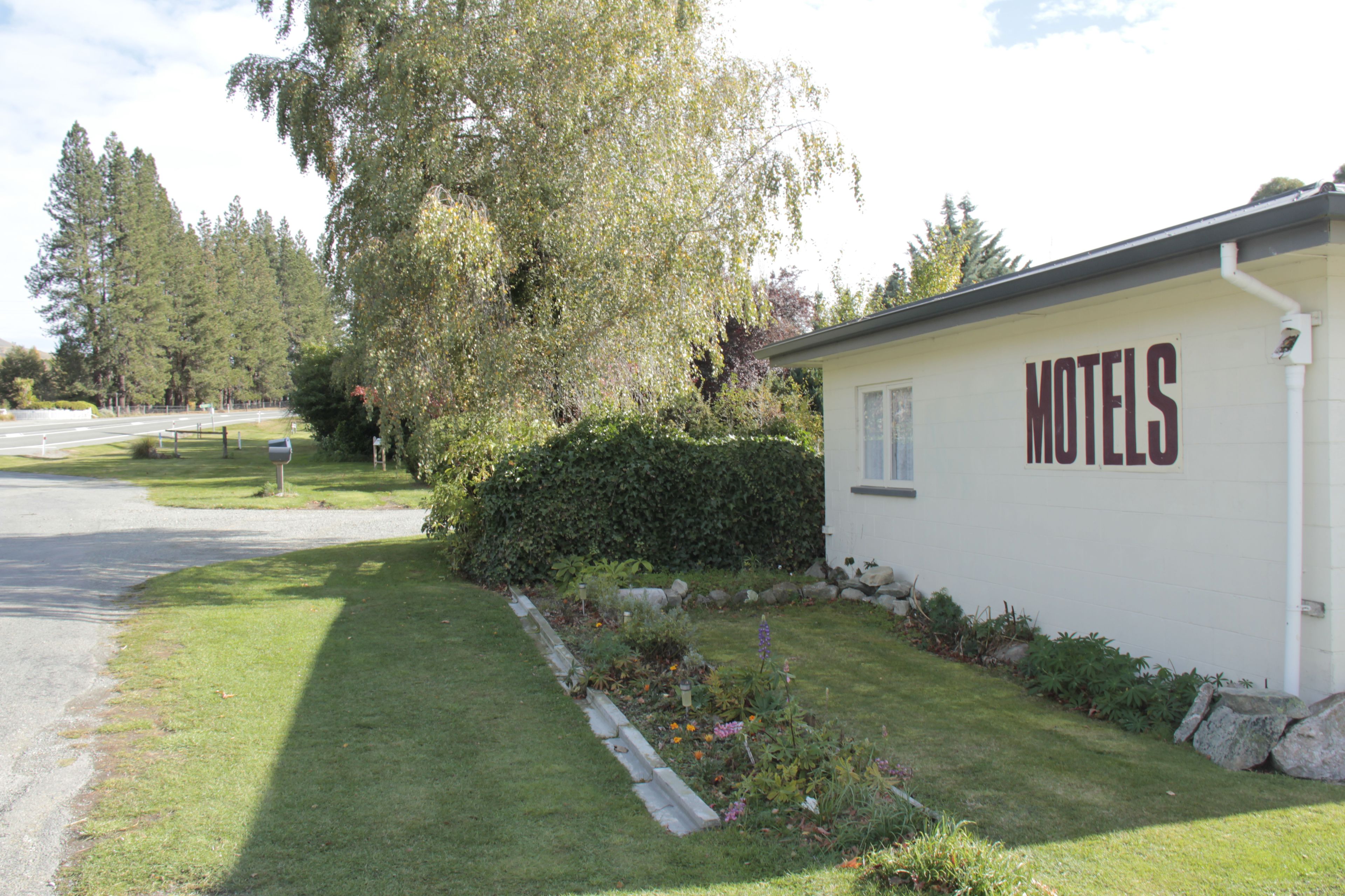 Un edificio blanco con la palabra "HOTELS" escrita en el costado, rodeado por un césped cuidado y un seto.
