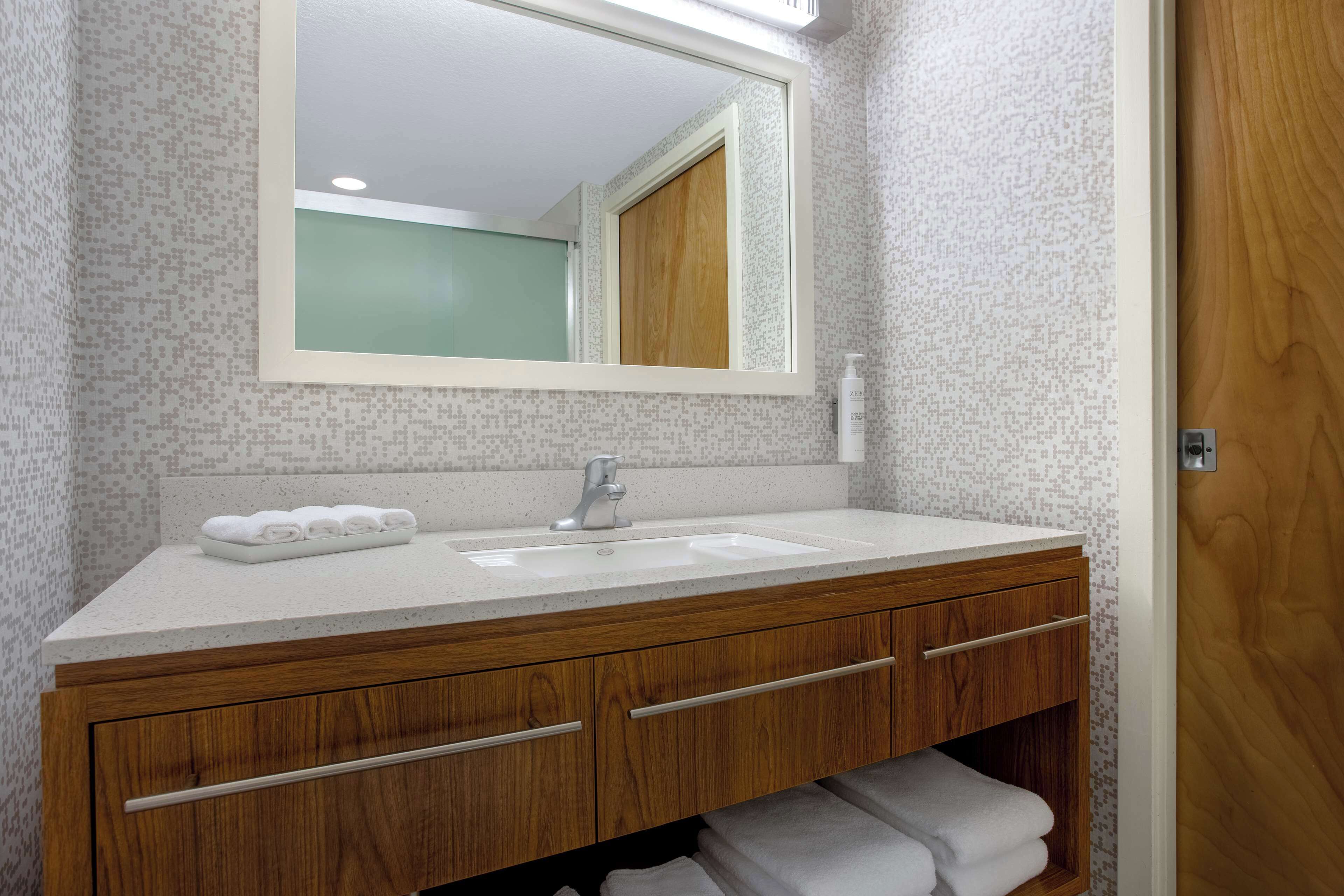 A bathroom with a white sink, wooden vanity, and a large mirror.