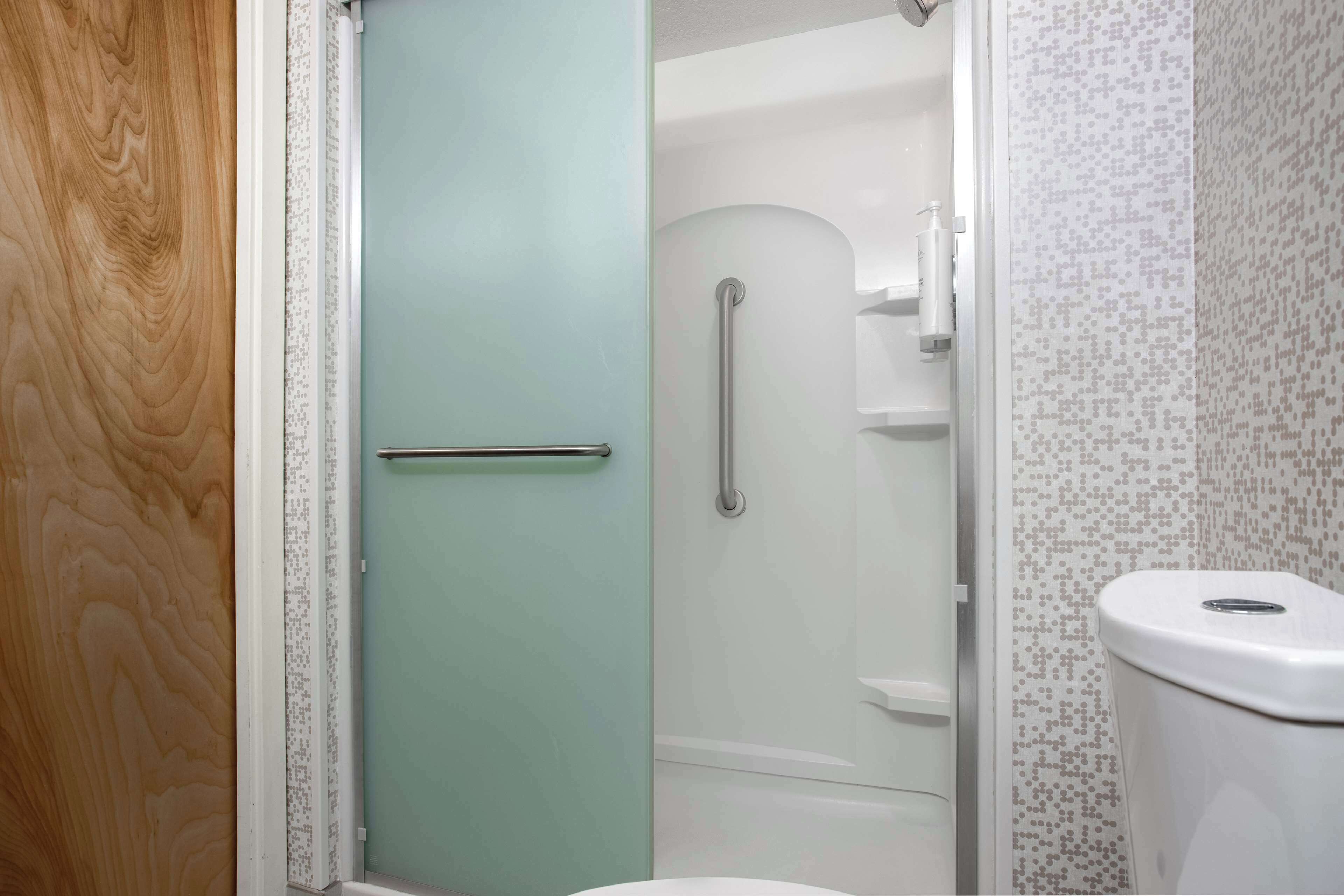 Une salle de bain avec une douche, des toilettes et une porte en verre.