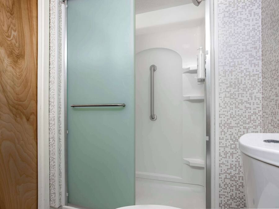 Un baño con ducha, inodoro y puerta de vidrio.
