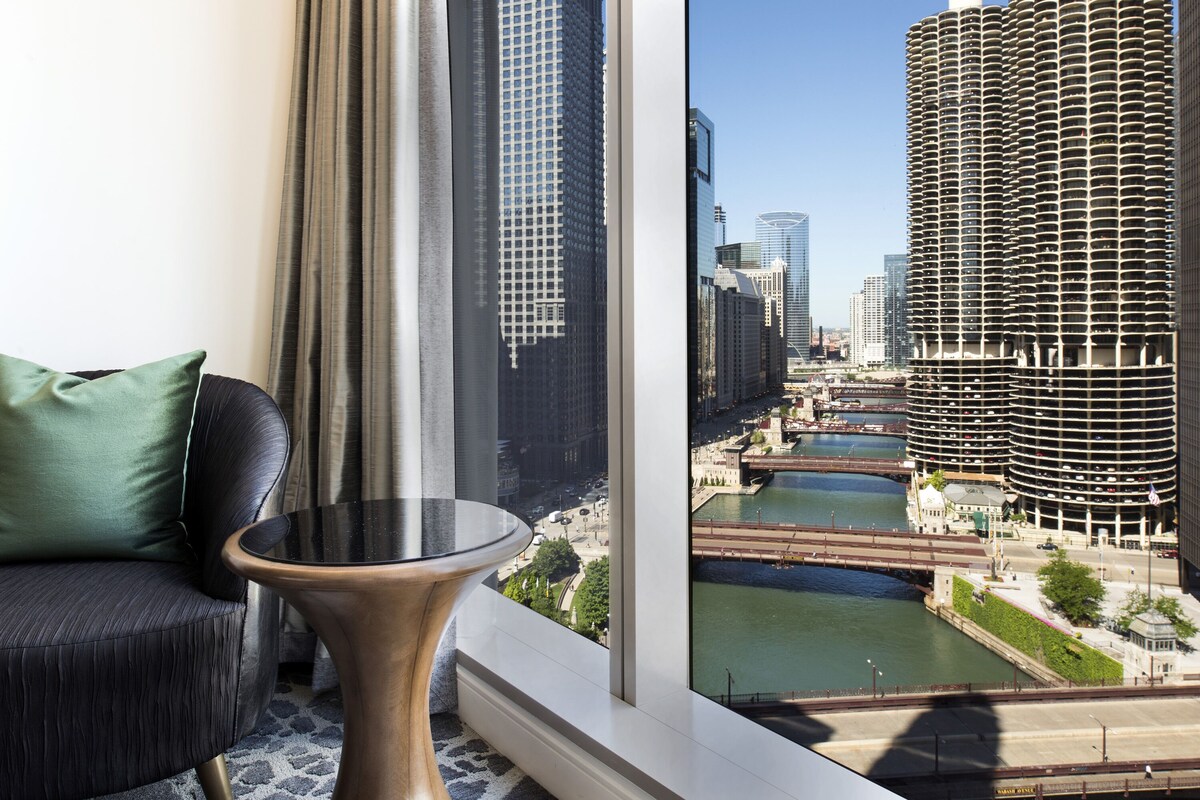 A modern room with a view of a river and high-rise buildings.