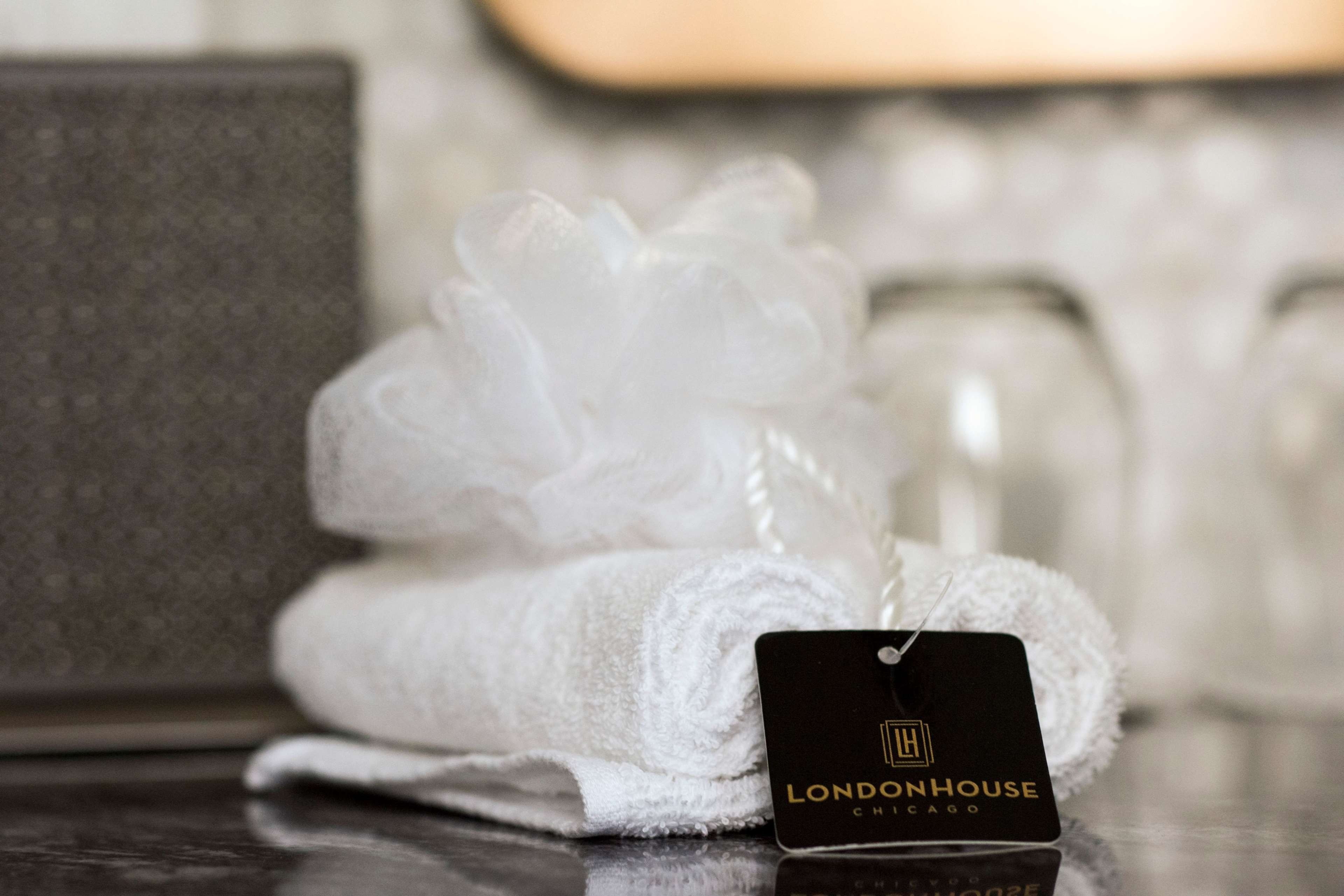 A neatly folded white towel with a tag labeled 'LONDONHOUSE CHICAGO' on a reflective surface.