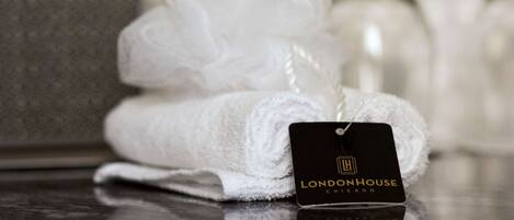A neatly folded white towel with a tag labeled 'LONDONHOUSE CHICAGO' on a reflective surface.