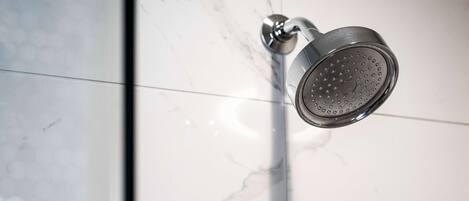 A showerhead mounted on a wall with a marble-like tile pattern.