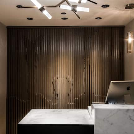 A modern reception desk with a marble top, an Apple laptop, and a Samsung charger.