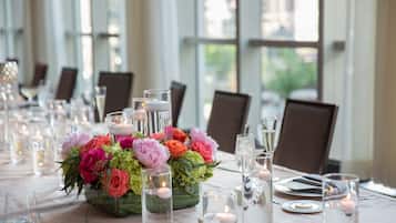 Una mesa de comedor adornada con velas, cristalería y un centro de mesa floral.
