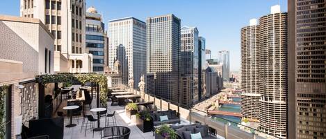 A rooftop terrace with outdoor seating and a view of the city skyline.