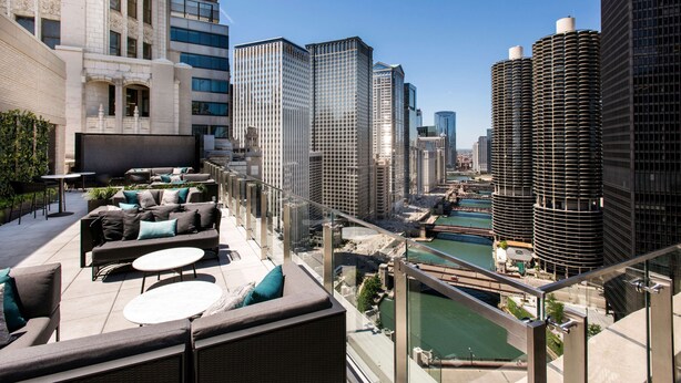 A rooftop terrace with outdoor seating, a view of the city skyline, and a river. - LondonHouse Chicago, Curio Collection by Hilton (Chicago)