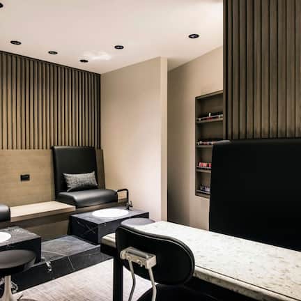 A modern bathroom with a black and white marble sink, a black chair, and a bench.