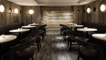 A modern interior with round tables and dark seating, featuring a central wall with a striped pattern.