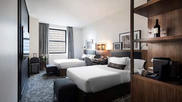 Ein Hotelzimmer mit zwei Betten, einem Schreibtisch, einer Kaffeemaschine und einem Bücherregal.