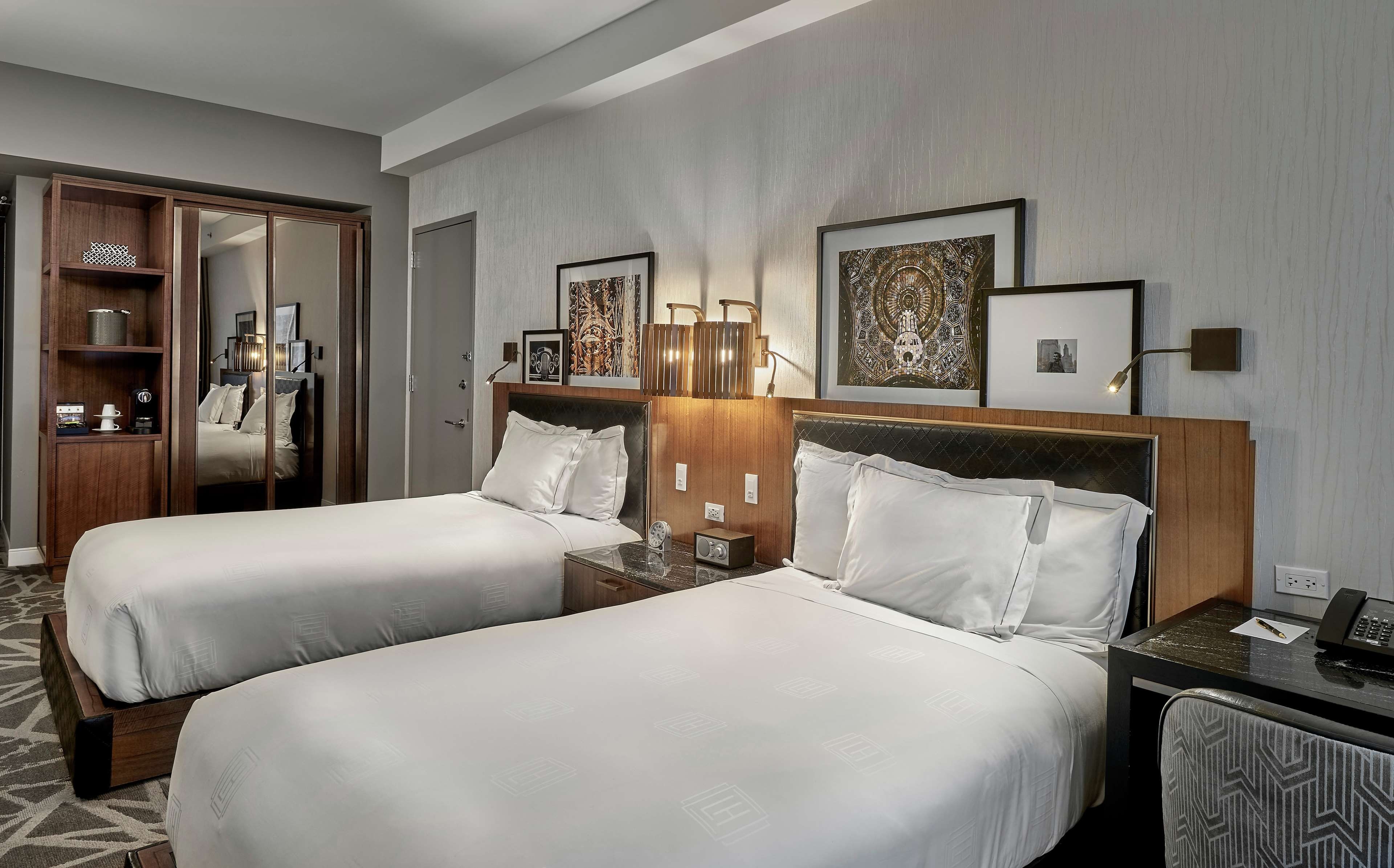 Ein Hotelzimmer mit zwei Betten, einem Schreibtisch mit Telefon und einem Kleiderschrank.
