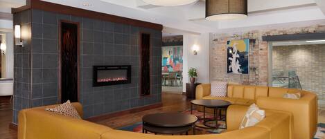 A modern living room with a fireplace, yellow sofas, and a large painting on the wall.